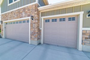 Two door garage on modern home with light green board and batten siding