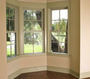 Inside of an unfurnished home with double-hung windows overlooking yard