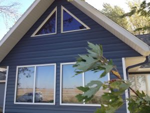 Close up of home with blue siding accented by white windows and triangular roof