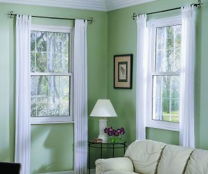 Cozy corner of mint green living room with white single-hung windows